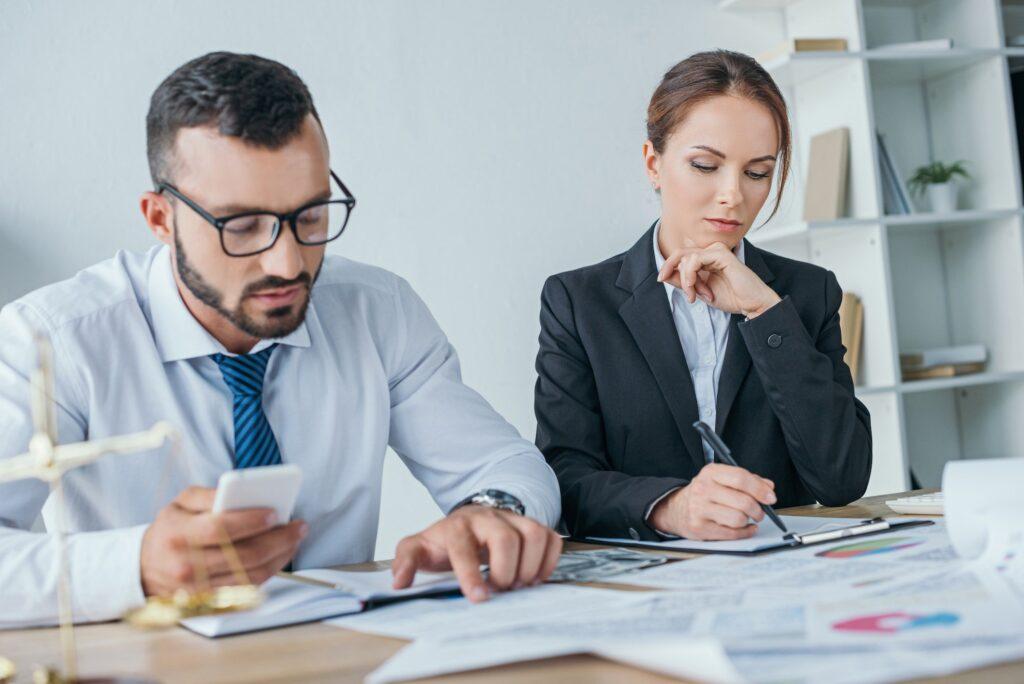 accountants working with documents and using smartphone in office
